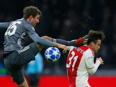 Gelandang Bayern Munchen Thomas Mueller (kiri) menendang kepala bek Ajax Amsterdam Nicolas Tagliafico dalam laga Grup E Liga Champions di Amsterdam, Belanda, Rabu (12/12). Mueller menendang Tagliafico dengan kaki kanannya. (AP Photo/Peter Dejong)