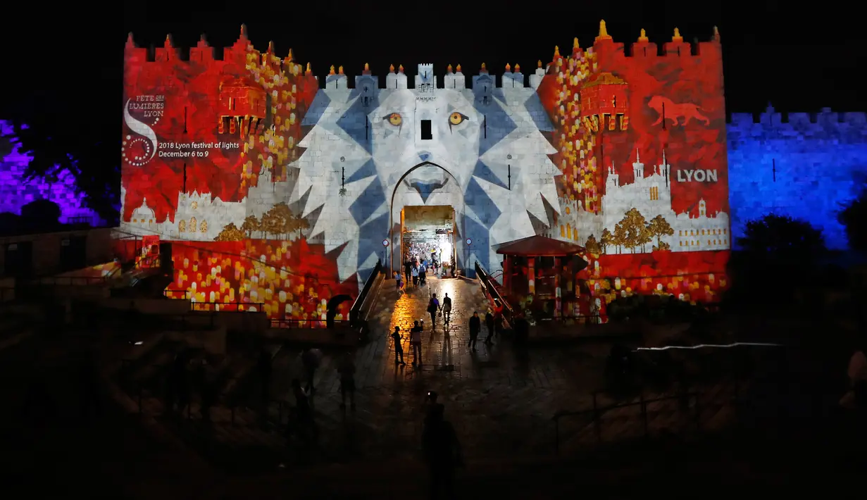 Orang-orang berjalan di dekat gerbang Damaskus selama festival cahaya di kota tua Yerusalem, 28 Juni 2018. Festival cahaya yang menampilkan karya seniman Israel dan internasional ini berlangsung setiap tahun di Kota Tua Yerusalem. (AFP / Ahmad GHARABLI)