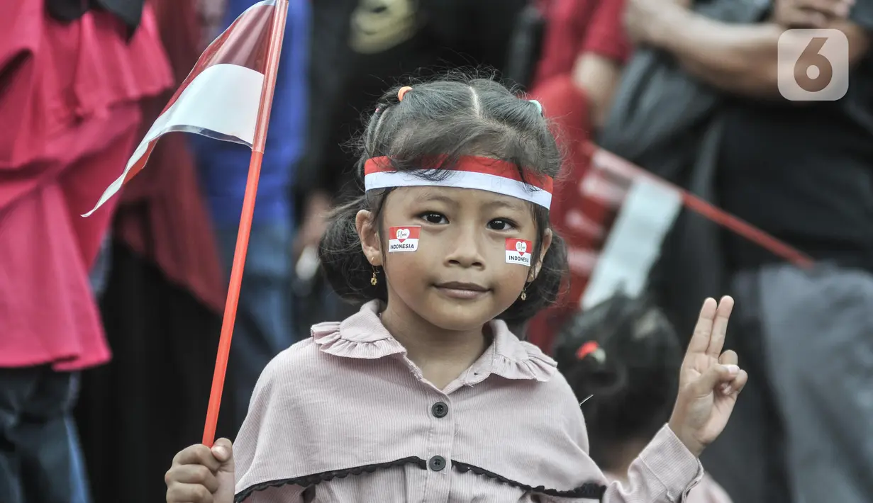 Seorang anak melihat Upacara HUT ke-77 Republik Indonesia yang disaksikan dari Taman Aspirasi Monumen Nasional (Monas), Rabu (17/8/2022). Setelah sempat ditiadakan selama 2 tahun akibat pandemi Covid-19, Upacara Peringatan Kemerdekaan Republik Indonesia disambut antusias warga dari berbagai daerah yang berdatangan untuk mengikuti meski hanya dari luar Istana Negara. (merdeka.com/Iqbal S Nugroho)