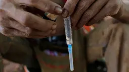 Seorang pria menyiapkan jarum suntik sebelum menyuntikan heroin ketubuhnya di jalanan Man Sam, Myanmar, 11 Juli 2016. Tanpa memikirkan sekelilingnya pengguna narkoba ini mengkonsumsi obat-obatan terlarang dimuka umum. (REUTERS/Soe Zeya Tun)