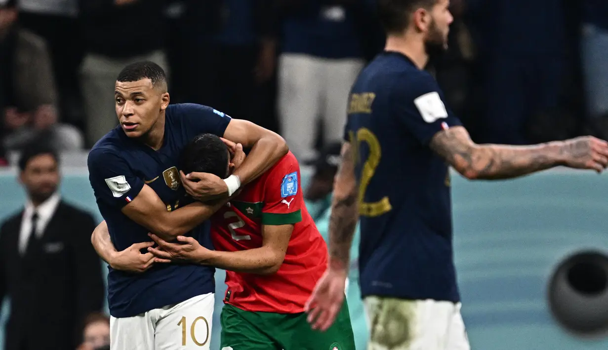 Pemain Prancis, Kylian Mbappe (kiri) menghibur pemain Maroko, Achraf Hakimi setelah laga semifinal Piala Dunia 2022 yang berlangsung di Al Bayt Stadium, Qatar, Rabu (14/12/2022) waktu setempat. Prancis menang dengan skor 2-0 melalui gol Theo Hernandez dan Randal Kolo Muani. (AFP/Gabriel Bouys)