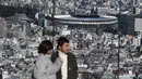 Orang-orang melihat Stadion Nasional Tokyo untuk Olimpiade dan Paralimpiade Tokyo 2020 setelah selesai direnovasi di Tokyo (30/11/2019). Stadion tersebut didesain oleh arsitek Jepang, Kengo Kuma, dan konstruksinya mewakili koneksi Jepang dengan alam bebas. (AFP Photo/Charly Triballeau)