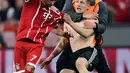 Seorang suporter menghampiri dan menarik jersey pemain Bayern Munchen,  Franck Ribery usai leg pertama semifinal Liga Champions melawan Real Madrid di Allianz Arena, Rabu (25/4). Ribery terlihat sempat kehilangan sedikit keseimbangan. (AFP/JAVIER SORIANO)