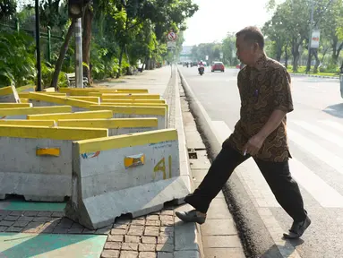 Pejalan kaki menghindari pembatas jalan yang menutupi trotoar di Jalan Medan Merdeka Utara, Jakarta, Rabu (3/7/2019). Pembatas jalan yang berada tidak pada tempatnya tersebut mengganggu pejalan kaki karena menutupi badan trotoar. (Liputan6.com/Immanuel Antonius)