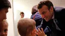 Presiden Prancis Emmanuel Macron berbicara dengan dengan anak-anak saat mengunjungi Graffiti's- Association Le Moulin Vert di Normandia, Prancis (5/4). (AP / Christophe Ena, Pool)