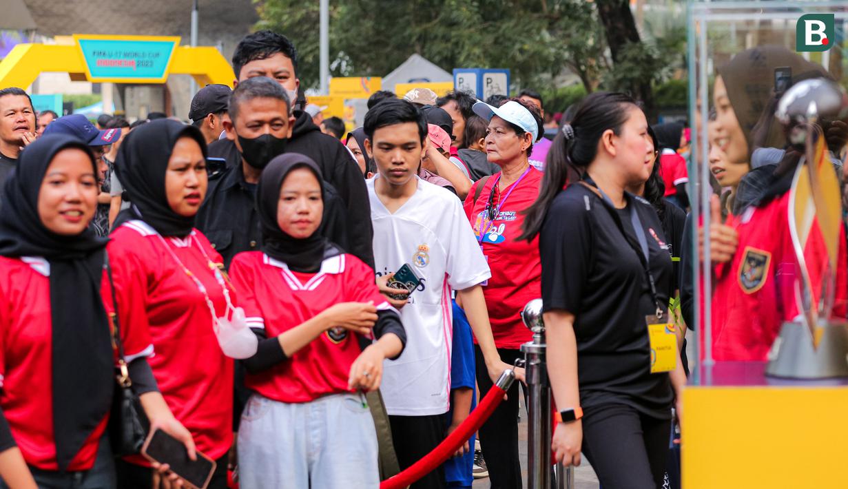 Sejumlah warga dengan antusias menunggu giliran untuk berfoto bersama trofi Piala Dunia U-17 2023 dalam rangkaian acara Trophy Experience saat Hari Bebas Kendaraan Bermotor di kawasan Bundaran HI, Minggu (15/10/2023). (Bola.com/Bagaskara Lazuardi)