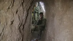Pejuang Suriah dukungan Turki memeriksa terowongan yang diduga dibangun oleh pejuang Kurdi di kota perbatasan Tal Talyyad, Suriah, Senin (21/10/2019). Pasukan Kurdi sepakat untuk menarik diri dari Tal Abyad ke Ras al-Ain. (Bakr ALKASEM/AFP)