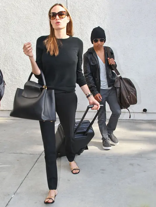Angelina Jolie mengaplikasikan nuansa hitam untuk terlihat simple. Bahkan ia menggunakan celana bahan dan sendal teplek untuk penampilannya. (pinterest.com)