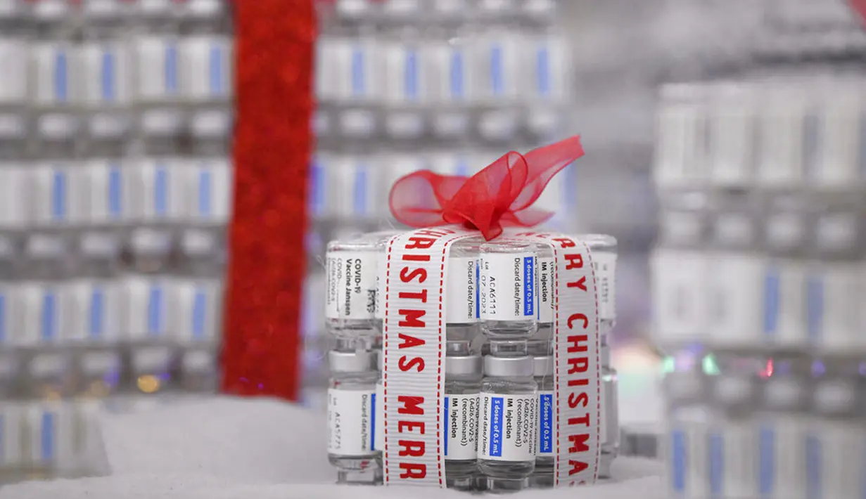 Kotak hadiah yang terbuat dari vaksin COVID-19 diletakkan di sebelah pohon Natal yang terbuat dari botol vaksin kosong di pusat vaksinasi di Bucharest, Rumania, 6 Desember 2021. Pusat vaksinasi COVID-19 membangun pohon Natal setinggi tiga meter dari 19 ribu botol vaksin. (AP Photo/Andreea Alexandru)