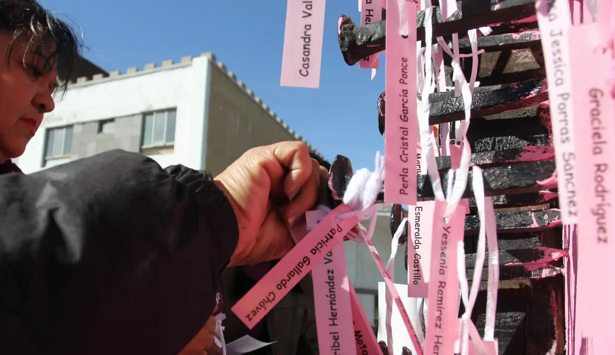 Ibu dan aktivis menempatkan nama-nama wanita yang dibunuh di Ciudad Juarez pada sebuah salib hitam di Jembatan Internasional Paso del Norte, Ciudad Juarez, Chihuahua, Meksiko, Rabu (7/3). (HERIKA MARTINEZ/AFP)