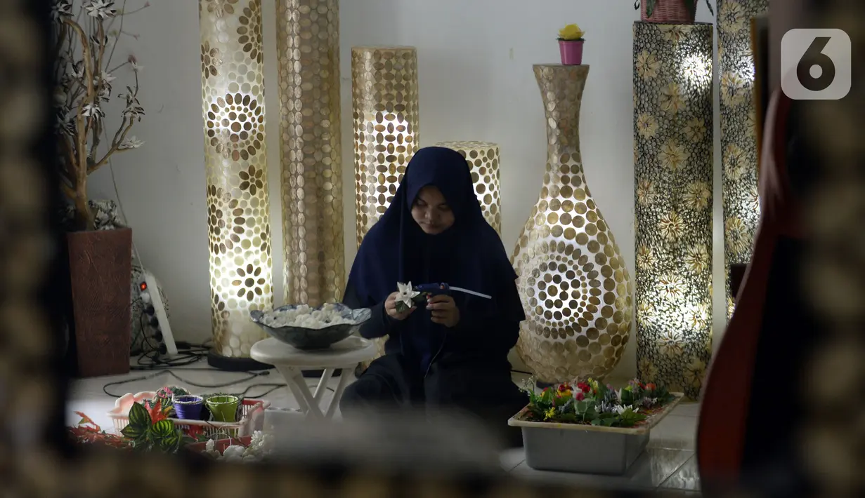 Perajin menyelesaikan pembuatan kerajinan tangan dari kulit kerang di Pamulang 2, Tangerang Selatan, Banten, Senin (20/7/2020). Aneka kerajinan tangan dengan motif bunga hingga ikan tersebut diolah dari limbah kulit kerang. (merdeka.com/Dwi Narwoko)