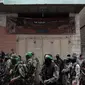 Tentara Hamas mengenakan topeng dan membawa senjata berjaga saat iring-iringan jenazah rekan mereka yang tewas di Deir el-Balah, Jalur Gaza (6/5). (AP/Khalil Hamra)