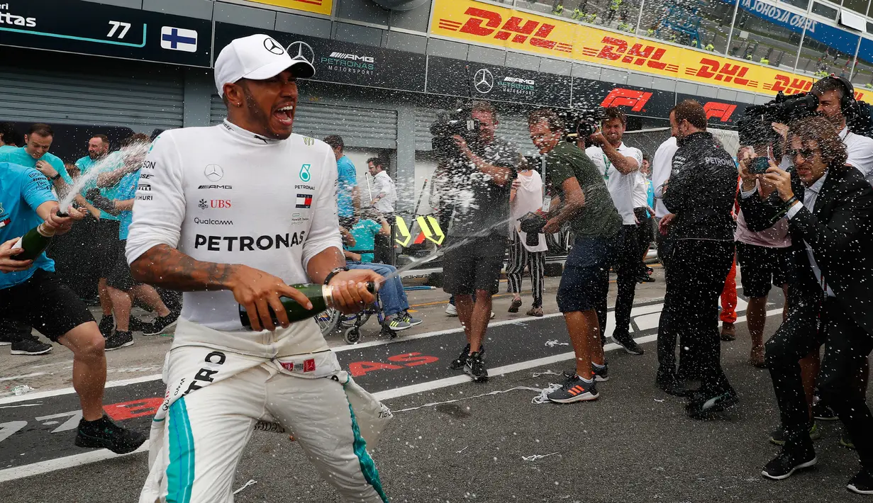 Pembalap Mercedes, Lewis Hamilton menyemprotkan sampanye saat merayakan keberhasilannya memenangkan GP Italia di Sirkuit Monza di Monza, Italia, (2/9). Saat ini Hamilton menempati urutan pertama klasemen dengan 231 poin. (AP Photo/Antonio Calanni)