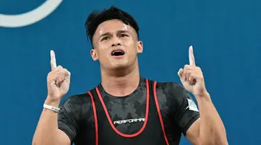 Rizki Juniansyah dari Indonesia melakukan selebrasi setelah memecahkan rekor di cabang olahraga angkat besi kelas 73kg putra selama Olimpiade Paris 2024 di South Paris Arena di Paris, pada 8 Agustus 2024 atau Jumat (9/8/2024) dini hari WIB. (Miguel MEDINA/AFP)