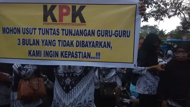 Seorang guru membawa beleho menuntut KPK mengusut tidak dibayarkannya TPP di Kota Pekanbaru.