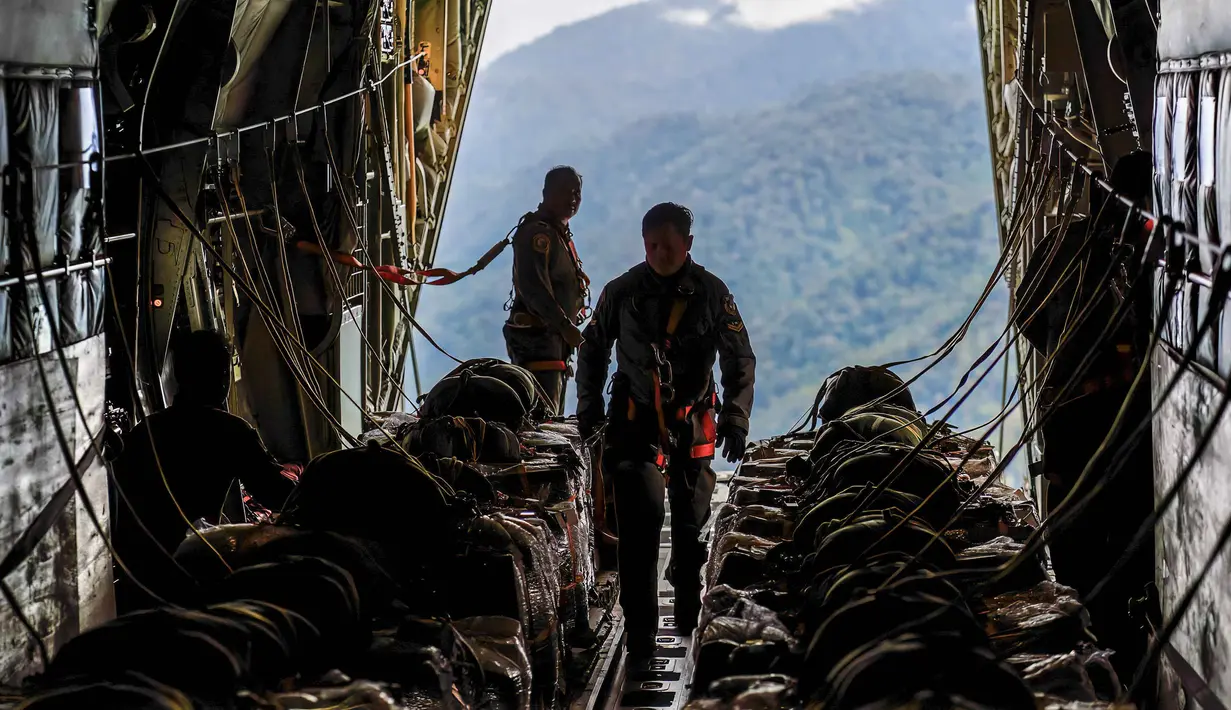 Pesawat-pesawat ini memiliki peran vital dalam menjangkau area terpencil dan membawa bantuan dalam jumlah besar. Tampak dalam foto, personel Tentara Nasional Indonesia (TNI) Angkatan Udara (AU) bersiap untuk menurunkan bantuan dari pesawat angkut militer di wilayah Gayo Lues, Aceh, yang terdampak banjir dan terisolasi pada Minggu 7 Desember 2025. (HENDRA SYAMHARI/AFP)
