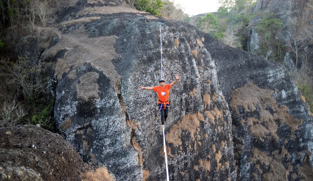 Gambar pada 9 September 2019 memperlihatkan atlet olahraga ekstrem, Andi Ardi berjalan di atas tali yang menggantung di ketinggian 740 meter (2.427 kaki) di Gunung Nglanggeran, Yogyakarta. Aksi itu sebagai bagian dari kampanye pariwisata untuk mempromosikan tempat yang indah. (AGUNG SUPRIYANTO/AFP)