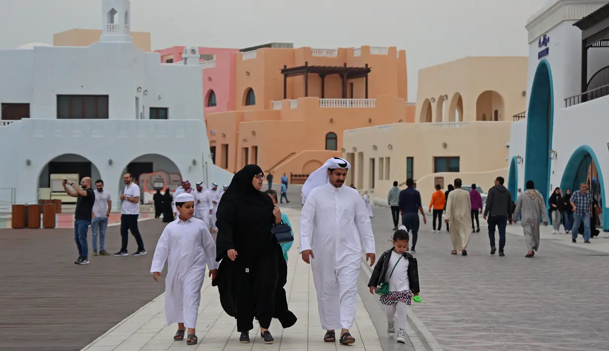Keluarga berjalan-jalan selama ajang Piala Dunia 2022 Qatar di Distrik Mina Doha pada 10 Desember 2022. Karena strukturnya yang semarak, distrik ini dapat dilihat dari kejauhan. Baik penduduk maupun pengunjung mengatakan hal pertama yang akan Anda perhatikan adalah warna bangunan yang mencolok. (AFP/Christina Assi)