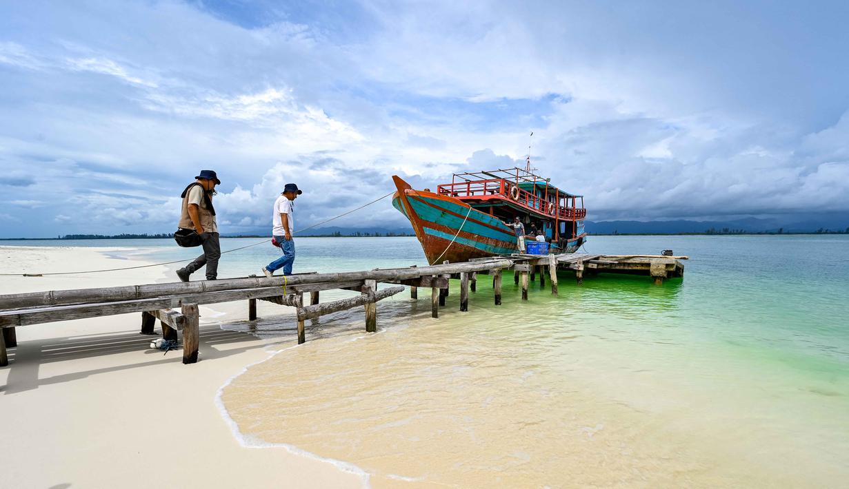 Di pulau ini, pengunjung dapat berenang, snorkeling, atau menikmati berbagai aktivitas air lainnya. Tampak dalam foto, orang-orang berjalan menuju perahu di Pulau Panjang, yang pernah menjadi objek sengketa perbatasan pulau antara Aceh dan Sumatera Utara, di Singkil, Provinsi Aceh bagian selatan, pada Rabu 12 November 2025. (CHAIDEER MAHYUDDIN/AFP)