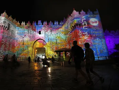Orang-orang berjalan di dekat gerbang Damaskus selama festival cahaya di kota tua Yerusalem, 28 Juni 2018. Festival cahaya yang menampilkan karya seniman Israel dan internasional ini berlangsung setiap tahun di Kota Tua Yerusalem. (AFP / Ahmad GHARABLI)