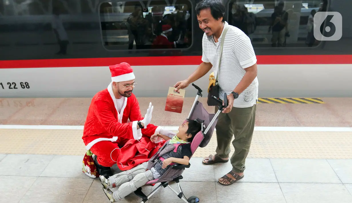 Pekerja yang mengenakan kostum Sinterklas membagikan hadiah Natal kepada penumpang kereta cepat Whoosh. (Liputan6.com/Herman Zakharia)