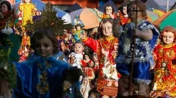 Seorang anak diangkat diantara patung simbol Bayi Yesus saat pemberkatan di Manila, Filipina (21/1). Santo Nino merupakan salah satu perayaan devosional paling besar di Filipina, yang dirayakan pada Minggu ketiga bulan Januari. (AP Photo / Bullit Marquez)