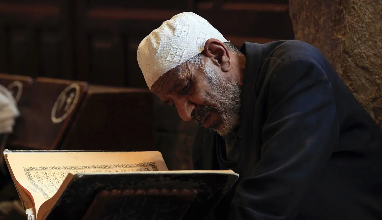 Seorang pria membaca Al-Quran selama bulan Ramadan di Masjid Agung Sanaa, Yaman, Minggu (26/4/2020). Masjid Agung Sanaa bagian dari Situs Warisan Dunia UNESCO. (Mohammed HUWAIS/AFP)