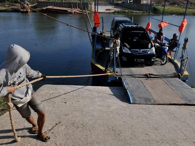 Pekerja menarik perahu eretan berisi kendaraan menyebrangi Sungai Citarum di Muara Gembong, Bekasi, Rabu, (29/7/2015). Kendaraan yang menyebrang menggunakan perahu eretan dikenakan biaya Rp.20.000 bagi mobil dan Rp 2.000 motor. (Liputan6.com/Johan Tallo)