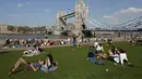 Orang-orang bersantai di tepi Sungai Thames dan Tower Bridge di London, Inggris, Jumat (20/4). Selain bermain di sungai, masyarakat Inggris juga biasa mengisi musim semi dengan berjemur di taman. (Daniel LEAL-OLIVAS/AFP)