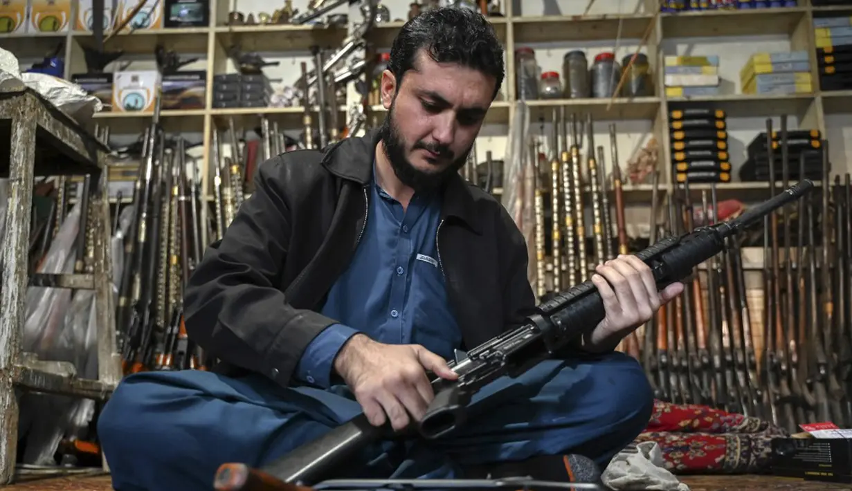 Seorang pedagang senjata Muhammad Jahanzeb memeriksa senjata otomatis di tokonya di Kota Darra Adamkhel, Pakistan, 4 Januari 2023. Pasar gelap senjata di Kota Darra Adamkhel dipenuhi dengan senapan Amerika palsu, replika revolver, dan AK-47 palsu. (Abdul MAJEED/AFP)