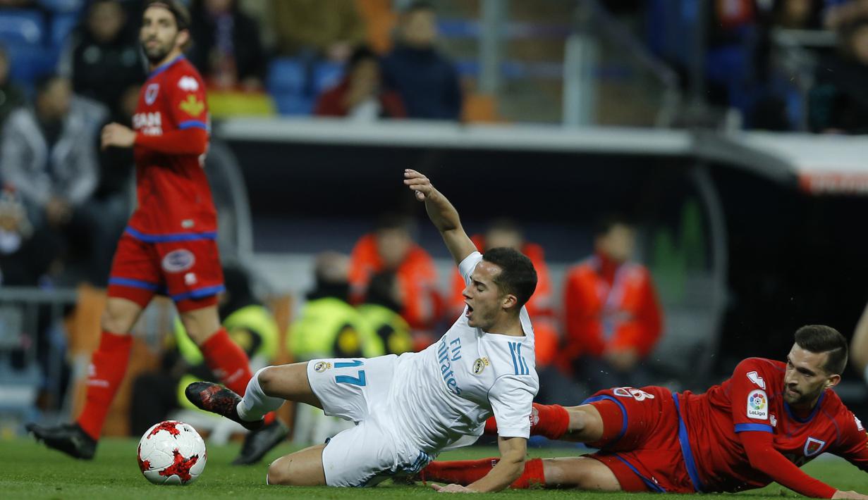 Pemain Real Madrid, Lucas Vazquez (tengah) jatuh saat berebut bola dengan pemain Numancia, Grego Sierra pada laga Copa Del Rey di Santiago Bernabeu stadium, Madrid, (10/01/2018). Real Madrid unggul agregat 5-2 atas Numancia. (AP/Francisco Seco)