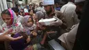 Relawan mendistribusikan kotak makanan untuk orang-orang yang berbuka puasa bersama selama bulan suci Ramadan di Peshawar, Pakistan, Senin (11/5/2020). Warga berbuka puasa bersama setelah pemerintah melonggarkan lockdown terkait pandemi virus corona COVID-19. (AP Photo/ Muhammad Sajjad)