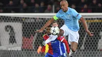 Aksi bek Manchester City, Vincent Kompany (kanan) menghalau bola dari kejaran pemain Basel, Dimitri Oberlin  pada laga 16 besar Liga Champions di Saint Jakob-Park Stadium, Basel, (13/2/2018). Manchester City menang 4-0. (AFP/Patrick Hertzog)