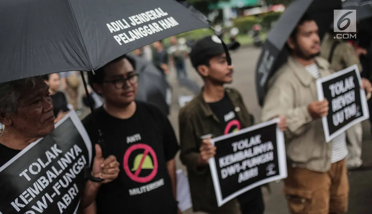 Aktivis Jaringan Solidaritas Korban untuk Keadilan menunjukkan poster tuntutan saat menggelar aksi Kamisan ke-575 di depan Istana Merdeka, Jakarta, Kamis (21/2). Aktivis menolak kembalinya militer untuk menduduki jabatan sipil. (Liputan6.com/FaizalFanani)