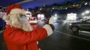 Penampil berkostum Sinterklas berinteraksi dengan pengunjung dalam acara drive-thru "WinterLights" di Pacific National Exhibition, Vancouver, British Columbia, Kanada, 12 Desember 2020. Acara ini untuk menyebarkan kegembiraan Natal kepada masyarakat di tengah pandemi COVID-19. (Xinhua/Liang Sen)