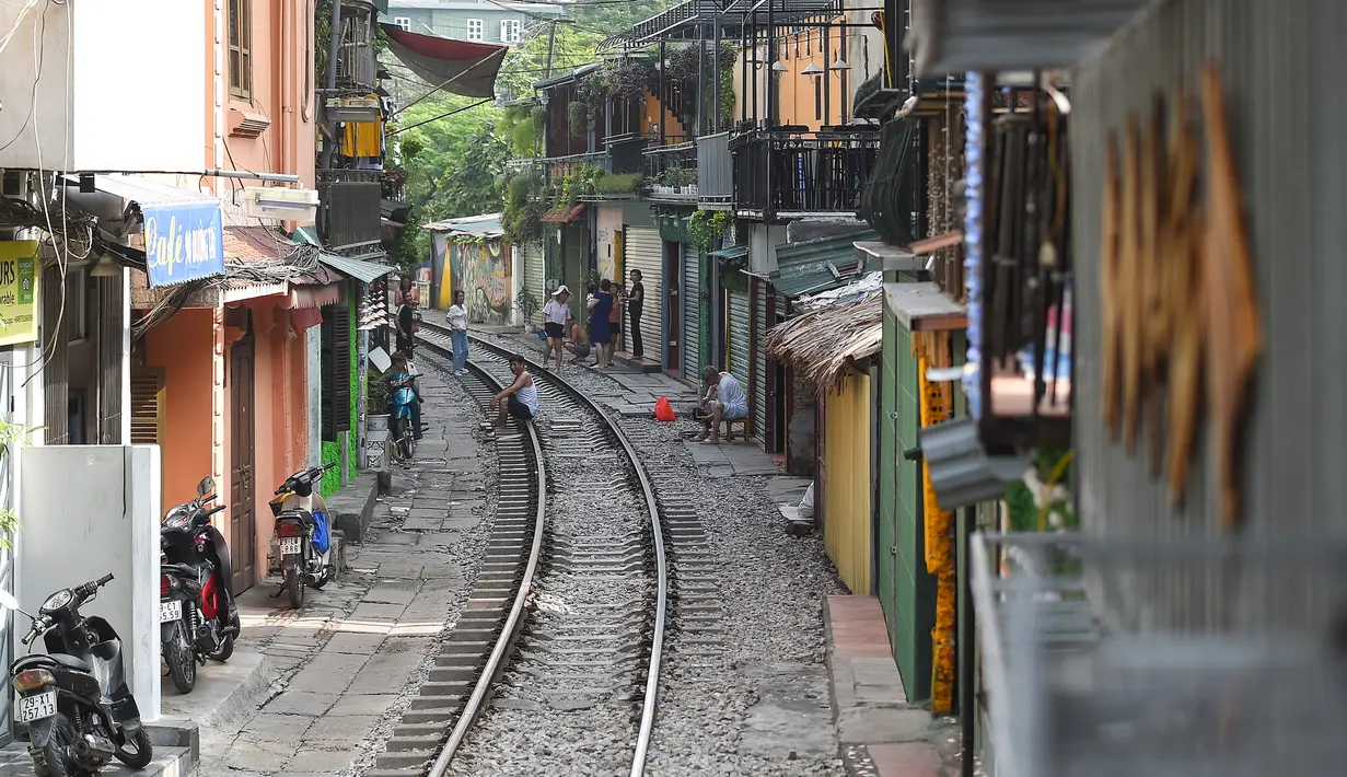 Warga duduk di atas rel kereta yang populer sebagai lokasi selfie di Hanoi, Vietnam, Kamis (10/10/2019). Banyaknya wisatawan nongkrong sampai selfie di lintasan kereta membuat pihak berwenang menutup jajaran kafe yang berdiri di samping rel tersebut. (Nhac NGUYEN/AFP)