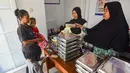 Ibu dan anaknya mengambil makan bergizi gratis (MBG) untuk dikonsumsi di rumah di Posyandu kawasan Limo, Depok, Jawa Barat, Selasa (14/7/2025).