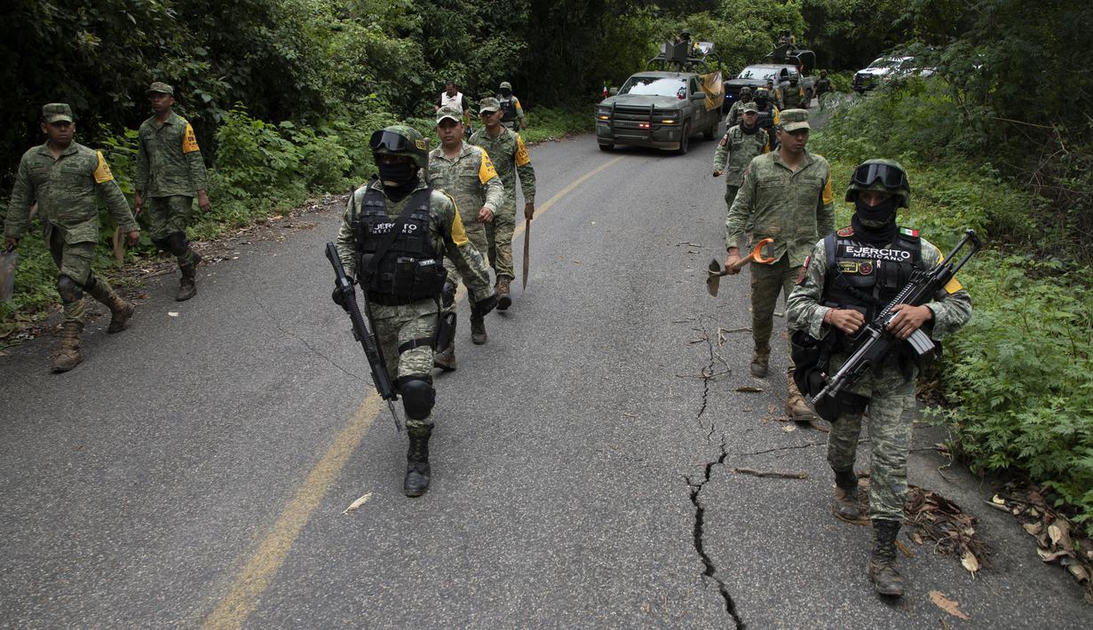 Tentara berjalan di jalan yang rusak, sehari setelah gempa bumi di dekat Chinicuila, negara bagian Michoacan, Meksiko, Selasa (20/9/2022). Dikutip dari NBC News, Rabu (21/9/2022), tercatat tiga gempa bumi dahsyat telah melanda Meksiko pada tanggal 19 September pada tahun 1985, 2017 dan sekarang 2022. (AP Photo/Armando Solis)