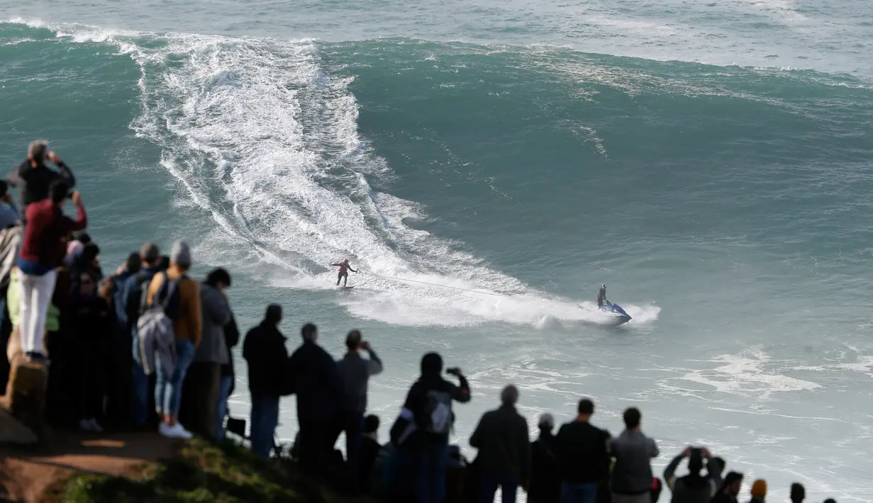 Penonton menyaksikan peselancar unjuk kebolehan dalam menaklukkan ombak besar di Praia do Norte atau Pantai Utara, Nazare, Portugal, Rabu (20/11/2019). Ombak di perairan ini disebut-sebut paling menantang dan paling berbahaya di dunia. (AP Photo/Armando Franca)