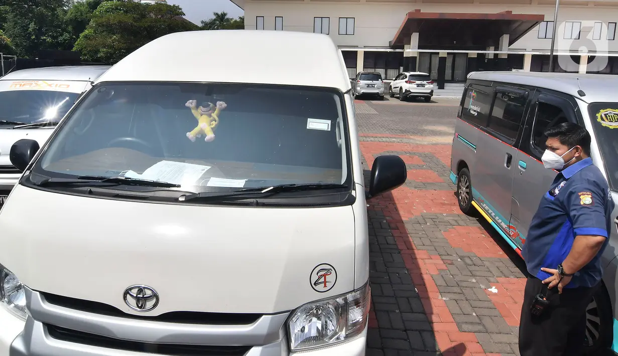 Petugas polisi memeriksa mobil travel gelap yang disita di halaman Polres Metro Kabupaten Bekasi, Jawa Barat, Senin (10/5/2021). Satlantas Polres Metro Bekasi mengamankan 32 travel gelap yang masih beroperasi saat larangan mudik dari tanggal 6-17 Mei 2021. (Liputan6.com/Herman Zakharia)