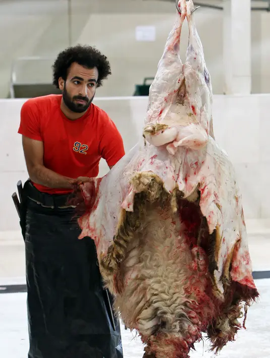 Mohammad Ibraheem saat memotong daging di sebuah rumah jagal hewan di hari ketiga Idul Adha di Kota Kuwait (13/8/2019). Karena kemiripannya dengan bintang Liverpool Mohamed Salah banyak orang meminta foto bareng dengannya. (AFP Photo/Yasser Al-Zayyat)