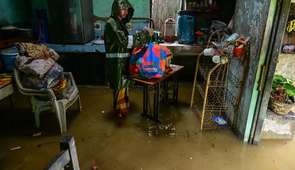 Sementara, Presiden Sri Lanka Anura Kumara Dissanayake telah memerintahkan pengerahan lebih dari 20.000 personel militer untuk melakukan operasi penyelamatan.  Tampak dalam foto, seorang pria mengemasi barang-barangnya sambil berdiri di dalam rumahnya yang sebagian terendam banjir setelah hujan deras di Kaduwela, pinggiran Kolombo, pada Jumat 28 November 2025. (Ishara S. KODIKARA/AFP)