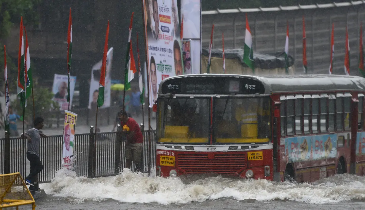 Sebuah bus menerjang banjir saat hujan deras di Mumbai, India (9/7). Departemen Meteorologi India mengeluarkan peringatan banjir akibat hujan deras di tempat-tempat terpencil di wilayah tersebut. (AFP Photo/Punit Paranjpe)