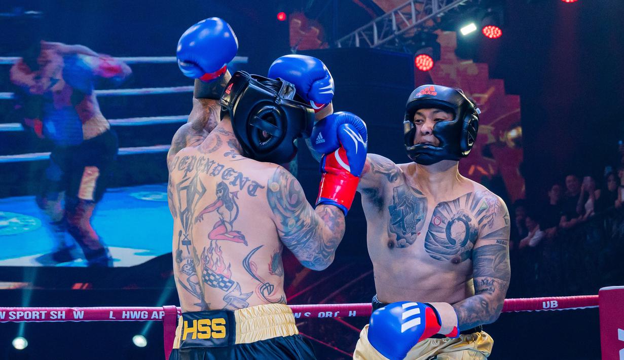 Komika, Uus (kanan), mendaratkan pukulan di kepala pemain drum Superman is Dead, Jerinx, saat pertandingan tinju Holywings Sport Show (HSS) Series 3 yang berlangsung di Atlas Super Club, Bali, Minggu (10/9/2023). (Dok. Holywings)