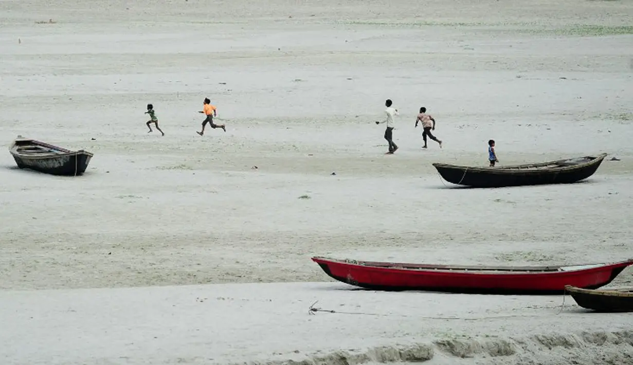 Anak-anak berlarian di dekat perahu nelayan di sebuah sungai kering di Allahabad, India (3/6/2015). Cuaca panas yang melanda India tidak hanya menewaskan ratusan warga, tetapi mengubah sungai menjadi seperti lapangan.  (AFP PHOTO/SANJAY Kanojia) 