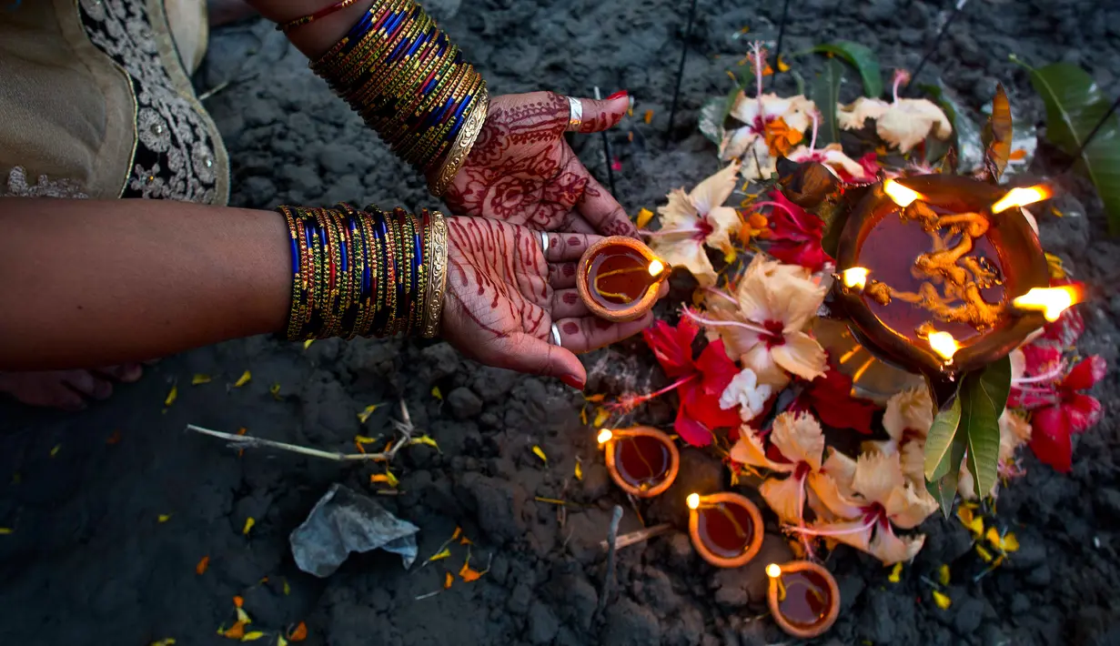 Umat Hindu India melakukan ritual selama Festival Chhath Puja di tepi sungai Brahmaputra, Gauhati, Selasa (13/11). Festival Hindu kuno ini dilakukan sebagai bentuk terima kasih kepada Dewa Matahari yang menopang kehidupan di bumi. (AP/Anupam Nath)