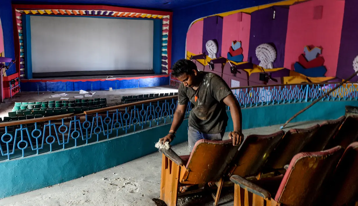 Pekerja membersihkan ruang bioskop sebagai persiapan kemungkinan pembukaan kembali setelah pelonggaran pembatasan Covid-19, di Chennai, Sabtu (3/10/2020). Kementerian Kesehatan India melaporkan pada Sabtu (3/10) total kematian di India akibat virus corona naik menjadi 100,842. (Arun SANKAR/AFP)
