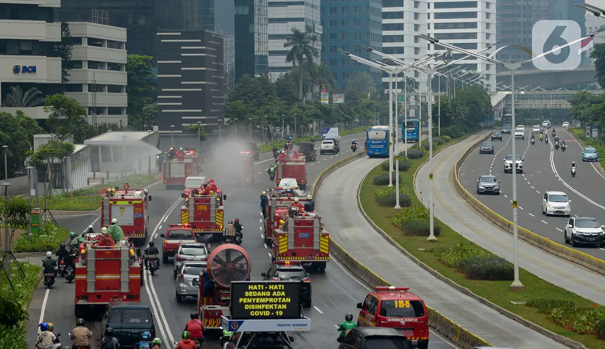 Petugas pemadam kebakaran (Damkar) dengan mobil pemadam melakukan penyemprotan cairan disinfektan di sepanjang jalan Thamrin-Sudirman, Jakarta, Sabtu (28/3/2020). Penyemprotan dilakukan untuk meminimalisir penyebaran COVID-19 di ruang udara dan ruas jalan. (merdeka.com/Imam Buhori)