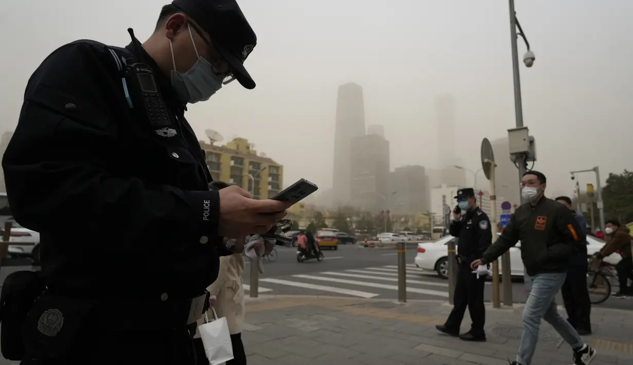 Petugas polisi China memantau persimpangan saat badai debu melanda Beijing, Jumat, 10 Maret 2023.Beijing sebelumnya terkenal karena kualitas udaranya yang buruk, tetapi kondisinya telah jauh lebih baik dalam beberapa tahun terakhir karena pihak berwenang mengambil kendaraan yang sangat berpolusi dari jalan dan memindahkan pembangkit listrik tenaga batu bara dan industri berat ke provinsi sekitarnya. (AP Photo/Ng Han Guan)