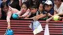 Petenis Jepang Naomi Osaka menandatangani bendera yang disodorkan penonton usai mengalahkan petenis Republik Ceko Marie Bouzkova pada Australia Terbuka di Melbourne, Australia, Senin (20/1/2020). Penonton menyodorkan topi, bendera, hingga bola untuk ditandatangani Naomi. (AP Photo/Lee Jin-man)